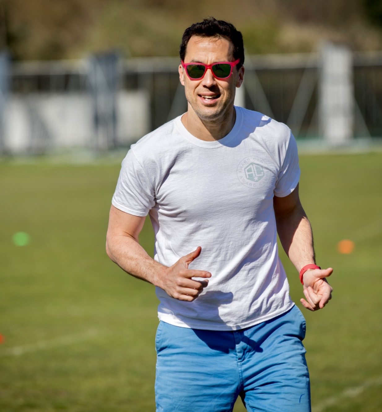 Five children posing together, smiling, on a grassy field.